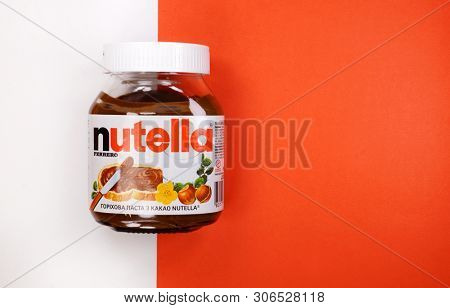 Kyiv, Ukraine - May 27, 2019: Nutella introduced to the market in 1964 by Italian company Ferrero. Nutella hazelnut on white and red background