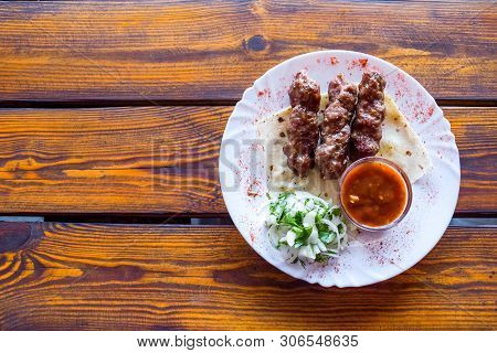 Portion Luleh Kebab On A Plate. Appetizing Dish On The Wooden Brown Table.