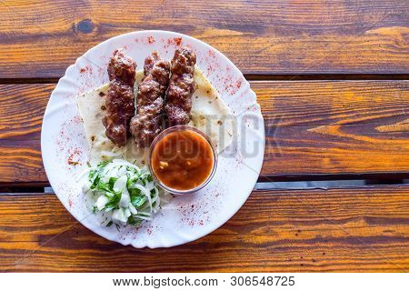 Portion Luleh Kebab On A Plate. Appetizing Dish On The Wooden Brown Table.