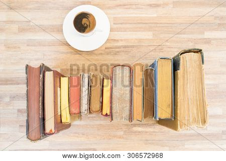 Books Row On Wooden Table With Cup Of Coffee, Top View Flat Lay. Reading, Learning, Literature Conce