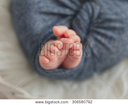 Little feet and toes of an infant sleeping tighly covered with soft warm blanket