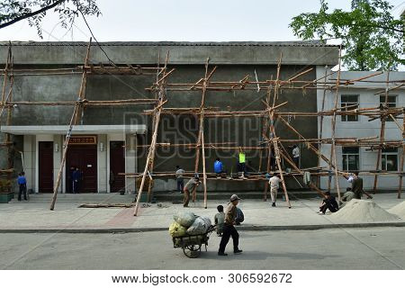 Wonsan, North Korea - May 4, 2019: Workers Use Primitive Wooden Scaffolding At Construction Site In 