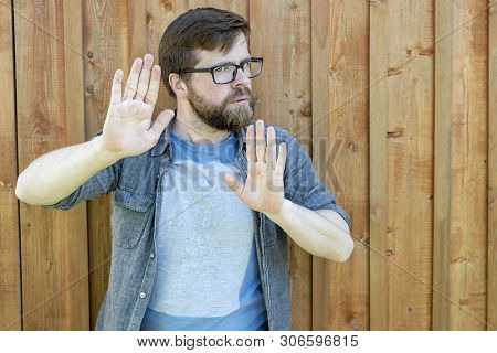 A Calm, Self-confident Bearded Man Pus His Palms As A Defense Or Calming Someone Down And Looking In