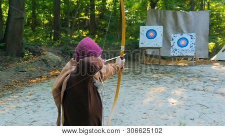 Medieval Male Archer Shooting Targets With Wooden Bow At Historical Festival. Archery And Medieval C