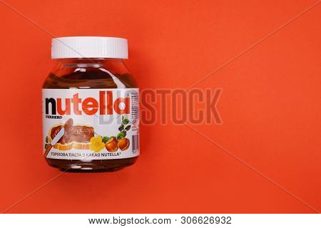 Kyiv, Ukraine - May 27, 2019: Nutella introduced to the market in 1964 by Italian company Ferrero. Nutella hazelnut on red background
