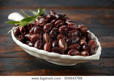 Pitted Kalamata Olives In Bowl On Rustic Wooden Background