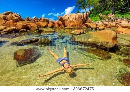La Digue, Anse Caiman, Natural Pool. Blonde Young Woman In Bikini Sunbathing On Crystal Water Of Swi