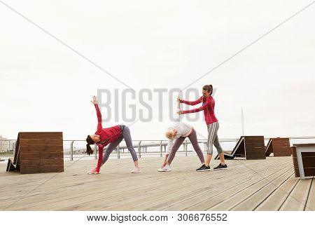 Wide Angle Portrait Of Senior Women Doing Yoga Outdoors During Morning Class On Pier, Copy Space
