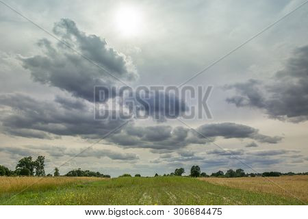 The Sun Behind Gray Clouds In The Sky, The Horizon And Field Stripes. Wolka Czulczycka, Poland