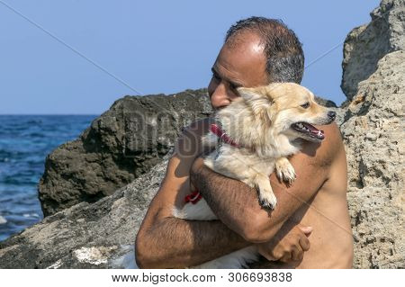 Cyprus, Karavas, Alsancak - June 10, 2019: Adult Male Cypriot Holding And Embracing Cute Happy Spitz