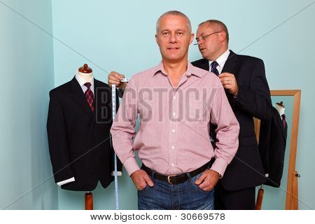 Photo d'un tailleur, mesurer la largeur de l'épaule d'un homme pour la pose d'un nouveau costume sur mesure