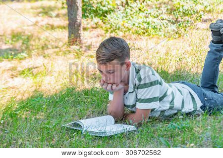 The Boy Lies In The Park On The Grass And Is Studying In Nature, Education And Science, The Book Is 
