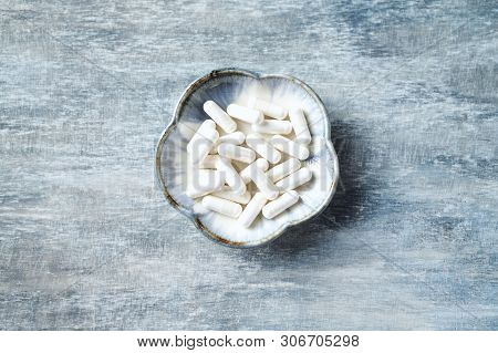 Theanine Capsules. Dietary Supplement.   Rustic Wooden Background. Top View. Copy Space.
