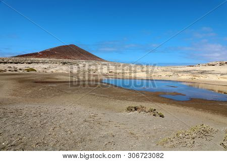 Amazing View Of Montana Roja Volcano With Pond In Natural Reserve Of Sand Desert In El Medano, Tener