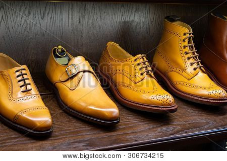 Tan full grain leather brogues shoes set on wooden display in in men shoes boutique store.