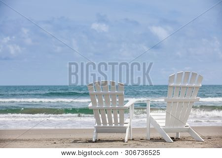 Empty White Wooden Chairs At A Paradisiac Beach On The Tropics In A Beautiful Sunny Day