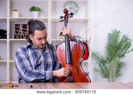 Young handsome repairman repairing violin