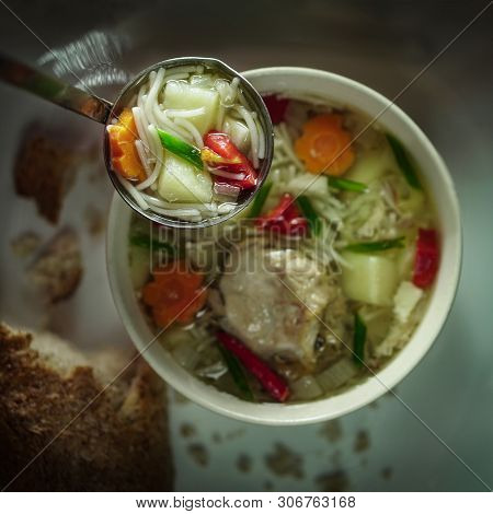 Chicken Noodle Soup In A Ladle And A Plate In The Background