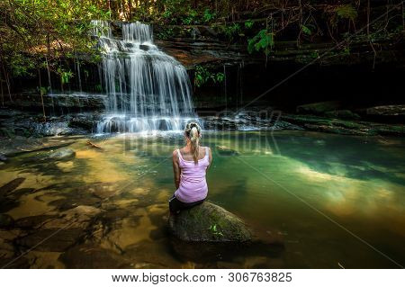Dappled Sunlight Warms Up The Little Rock Pool At A Waterfall. Woman Sitting On A Rock Enjoying The 