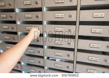 Close-Up of Woman Hand Insert a Key to Unlock Mailbox Locker in Apartment, Interior Mail Letterbox Cabinet in Condominium. Row of Post Locker in Residential Building.
