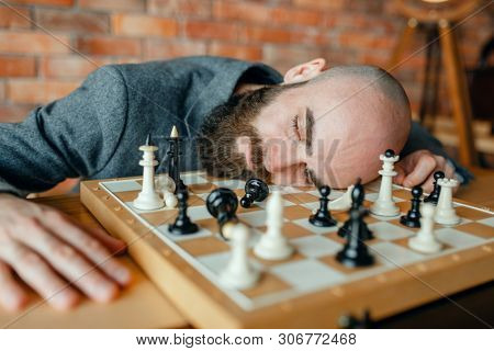 Tired male chess player sleeping on the board