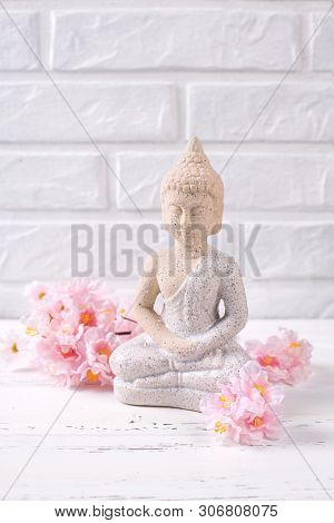 Decorative Buddha And Pink  Cherry Flowers Near By White Brick Wall. Spa Or Still Life  Layout. Sele