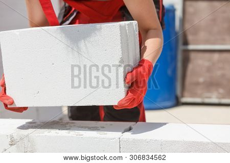 Unrecognizable Woman Working On Construction Site, Building House, Installing Gray Airbricks. Indust