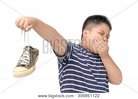 Disgusted Fat Boy Holding A Pair Of Smelly And Stinky Shoes Isolated On White Background,
