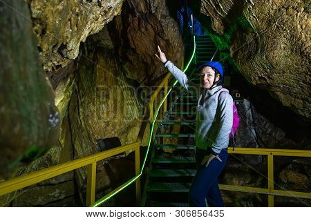 Young Woman With Helmet Pointing To Stairs In Ialomita Cave, Bucegi Mountains. A Cave In Bucegi Moun