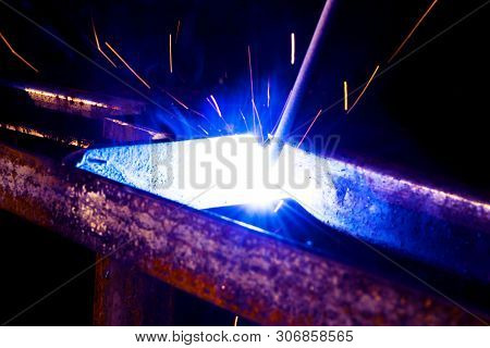 Welder Worker Performs Jump Welding. Man Welder In Protective Gloves Performs Arc-welding Process Of