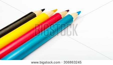 Four Colored Pencils. The Colors Cyan, Magenta, Yellow And Black. The Concept Of Polygraphy.