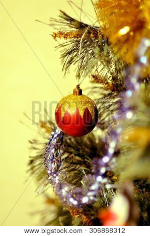 Red Ball On A Branch Of A Christmas Tree Cllose Up.