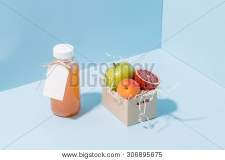Peach Juice In A Bottle And Fresh Apricot, Apple And Blood Orange Resting In Disposable, Compostable