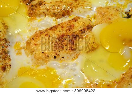 Close Up View Of The Fried Eggs On A Frying Pan. Salted, Spiced And  With Cheese And Fried Bread Sur