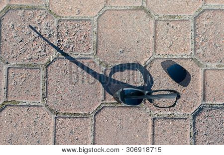 The Broken Sun Glasses Lying On The Flagstone Pedestrian Walkway, Road