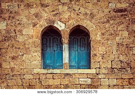 Ancient architecture background, two little windows with blue wooden shutters among great stony wall, house of God, old monastery, Lebanon