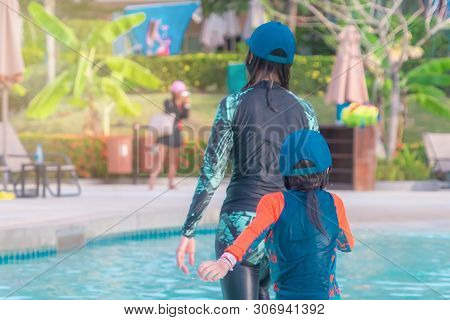 Mother And Daughter Is Walking In A Swimming Pool