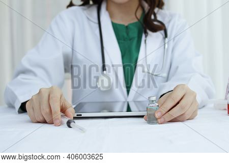 Hand Female Doctor Has Vaccine Bottle And Syringe On The Work Table,working Doctor,white Office Of T