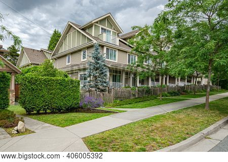 Row Of Townhouses With Concrete Pathway In Front On Couldy Day In Vancouver, Bc