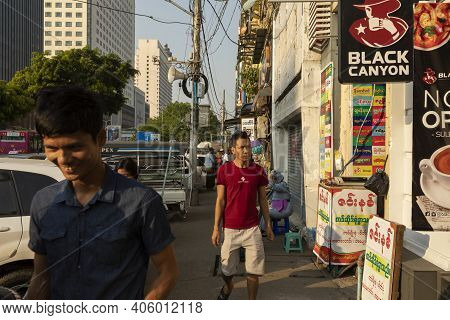 Yangon, Myanmar - December 19, 2019: Pedestrians Walking Along The Sidewalk Of Sule St, Full Of Traf