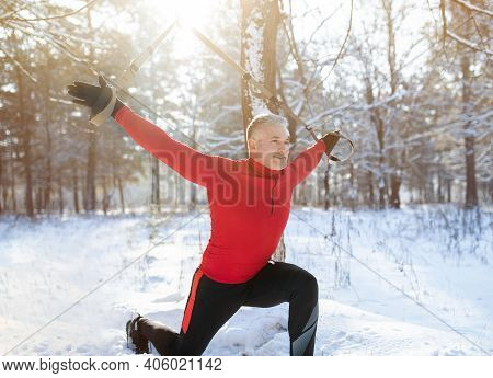 Trx Suspension Training Concept. Athletic Senior Man Working Out With Sports Equipment On Snowy Wint