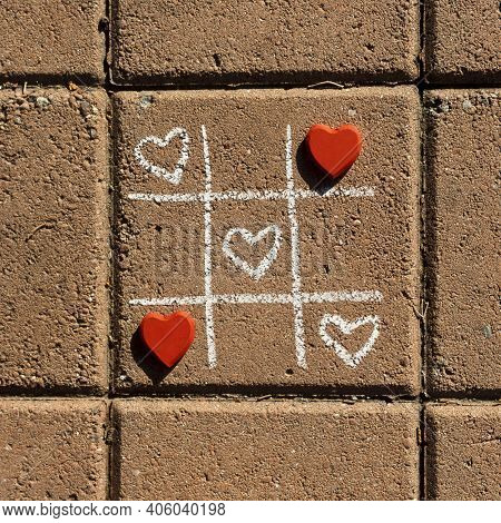 Chalk Tic Tac Toe Game With White And Red Hearts On Sidewalk