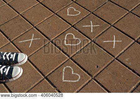 Chalk Tic Tac Toe Game On Sidewalk With Heart Drawings Instead Of Noughts And A Pair Of Sneakers