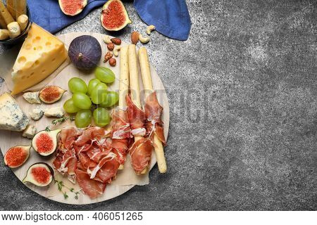 Board With Delicious Figs, Cheese, Grapes And Bread With Proscuitto On Grey Table, Flat Lay. Space F