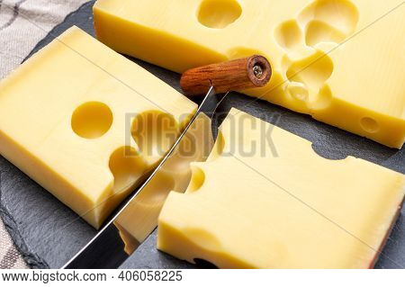 Block Of Swiss Medium-hard Yellow Cheese Emmental Or Emmentaler With Round Holes And Cheese Knife
