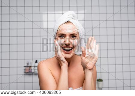 Cheerful Woman With Naked Shoulders Showing Palm With Foam Cleanser In Bathroom