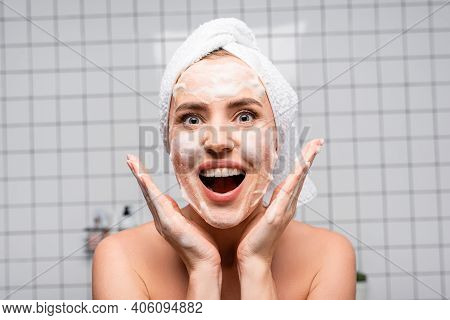 Amazed Woman With Naked Shoulders Applying Foam Cleanser In Bathroom