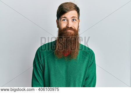 Redhead man with long beard wearing casual clothes puffing cheeks with funny face. mouth inflated with air, crazy expression. 