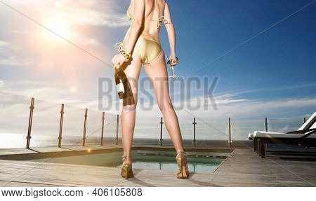 Portrait of sexy woman in bikini holding bottle of champagne
