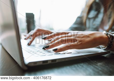 Close Up Of Unrecognizable Womans Hands With Dark Nailpolish Using Grey Laptop Computer On Desk